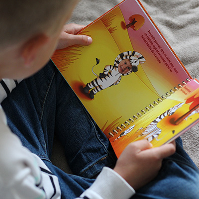 Enfant souriant qui regarde un livre avec sa photo