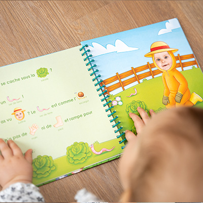 Enfant souriant qui regarde un livre avec sa photo