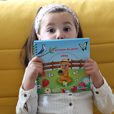 Enfant souriant qui regarde un livre avec sa photo