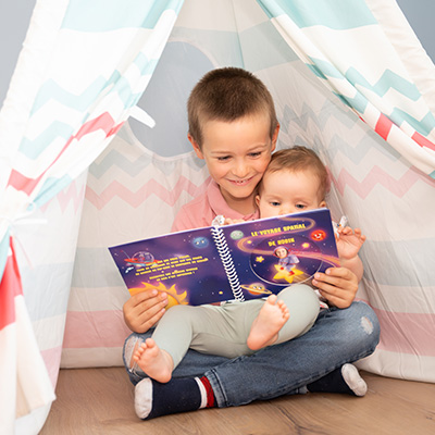 Enfant souriant qui regarde un livre avec sa photo