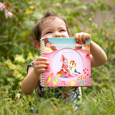 Enfant souriant qui regarde un livre avec sa photo